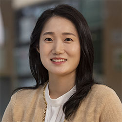 Uran Oh is an Asian woman with a meduim-long black hair, wearing a beige-color cardigan on top of a white blouse, smiling.